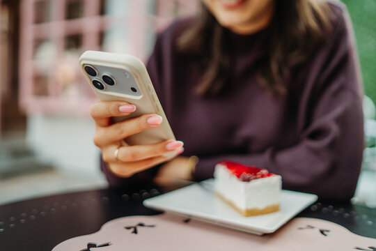 Woman photographing cheesecake with a smartphone at a cafe