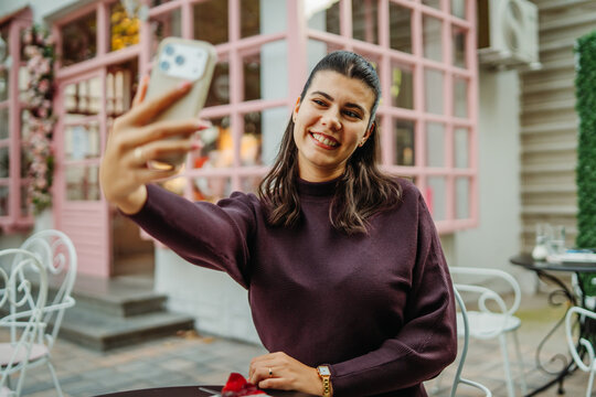 Woman taking a selfie at an outdoor cafe