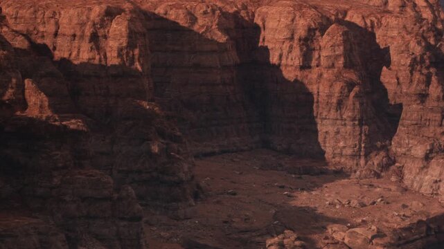 A canyon can be seen in an arid area. The scene shows large rock formations and a dry riverbed under bright daylight. The place appears remote with minimal vegetation.