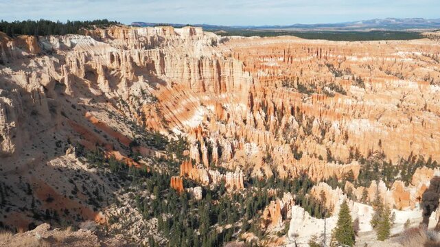 Bryce canyon national park utah, showcasing panoramic landscape of sandstone hoodoos and pine forests across sunlit rock amphitheater, with dramatic red rock formations shaped by erosion