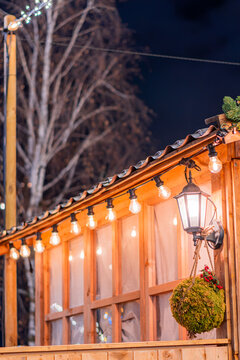 View of a wooden Christmas market stall decorated with glowing string lights, a vintage lantern, and a hanging moss ball in Montreux, Vaud, Switzerland.