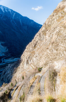 View of the famous switchback road of Lacets de Montvernier carved into the steep mountainside with rocky slopes and sparse vegetation in Montvernier, Auvergne-Rhone-Alpes, France.