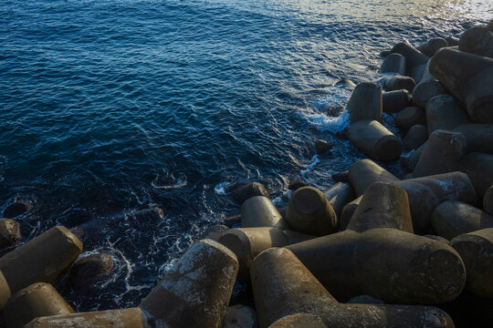 Concrete tetrapods lining a breakwater against deep blue ocean ripples at Daepo port in Sokcho-si South Korea during autumn.
