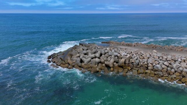 An aerial shot of the Atlantic Surf Beside a Concrete Breakwater and Sandy Beach