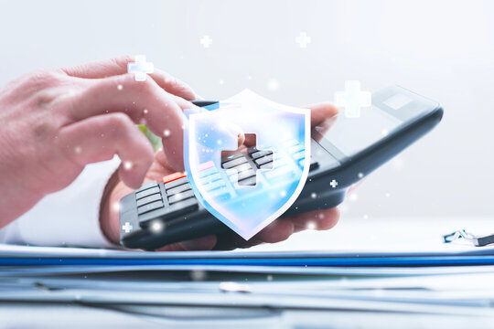 Hand holding calculator with glowing medical protection shield and healthcare cross icon. Health insurance, medical cost calculation and financial protection concept for healthcare expenses.