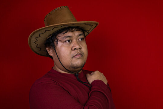 A dignified portrait of a young Asian male looking away with a serious, contemplative expression while holding his collar. The reflective subject is sharply dressed in a casual maroon