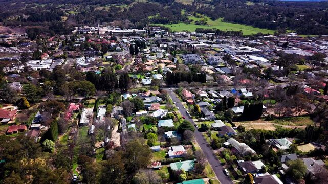 High angle drone aerial view of Bowral town centre and main street rooftops in the Southern Highlands, New South Wales, Australia on a bright day
