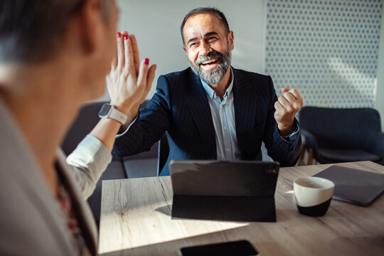 Smiling coworkers high five during office meeting