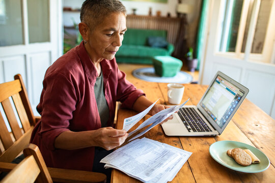 Older woman reviewing bills with laptop at home