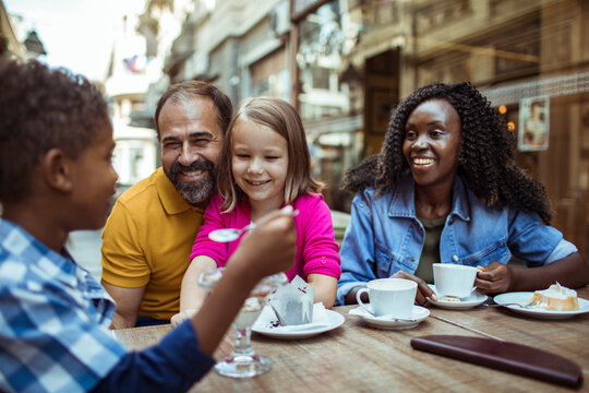 Two adults and two children enjoying dessert at outdoor cafe