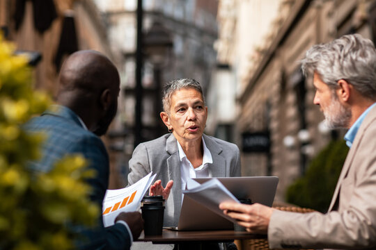 Senior businesswoman leading discussion at outdoor cafe meeting