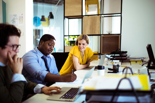Colleagues discussing work as man takes notes in office