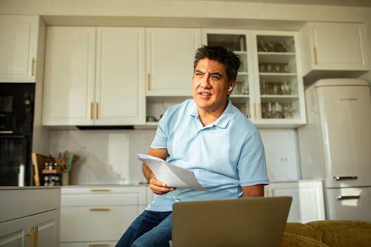 Man on video call with paperwork in kitchen