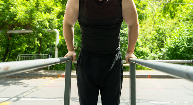 A muscular man performing dips on parallel bars
