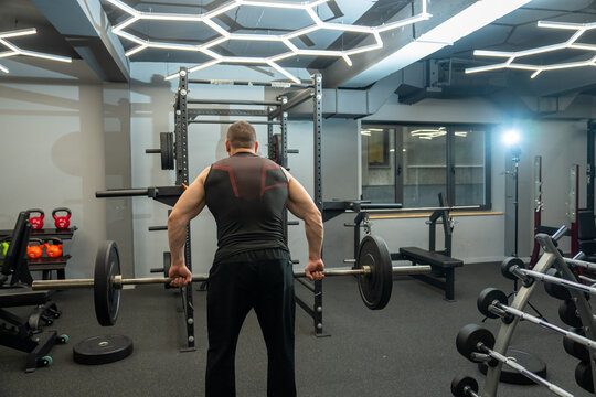 A muscular man lifts a barbell.