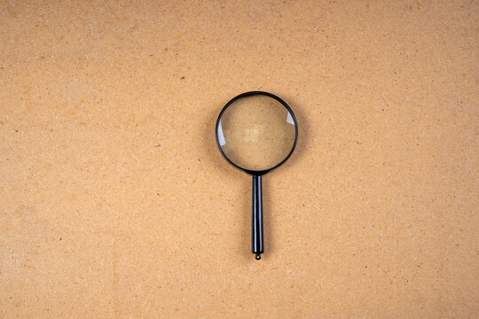 There is a magnifying glass on a light brown background.