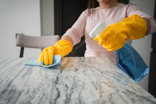 Washes the kitchen table with gloves