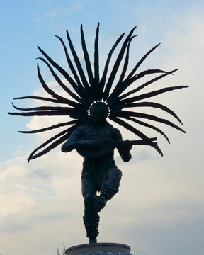 Conchero dancer monument silhouette against blue sky with white clouds in Queretaro historic district showcasing traditional Mexican culture and bronze sculpture art on Hill of Sangremal