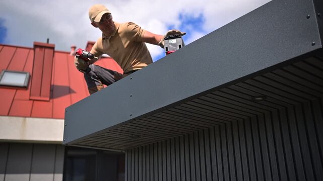 Roofer aligning dark fascia panels on a flat roof