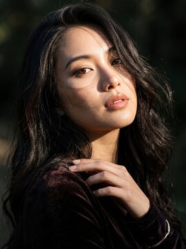 Portrait of young Asian woman with long dark hair outdoors