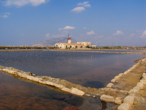 View of the historic saltworks windmills at the salt pans in Trapani, Sicily, Italy.