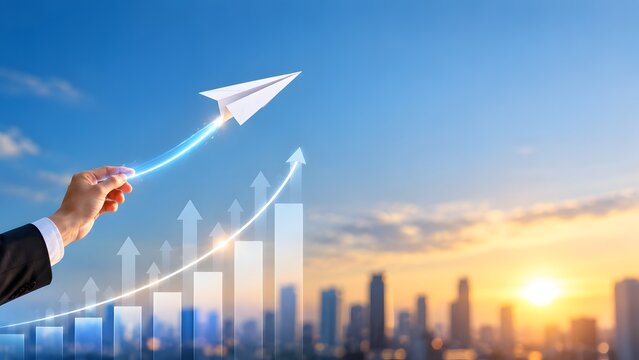 Business growth trajectory concept hand launching paper airplane over glowing financial chart arrows against city skyline at sunrise