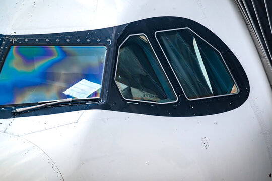 View of the cockpit windows of an airplane parked at RIOgaleao International Airport, showing the reflective glass and window frame in Rio de Janeiro, Rio de Janeiro, Brazil.