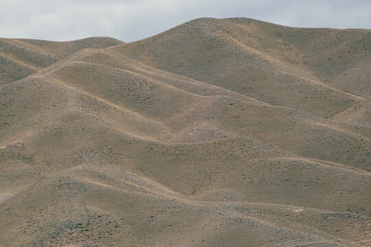 View of the arid, rolling hills of the Black Canyon landscape under a cloudy sky in Aktogay, Almaty Region, Kazakhstan.