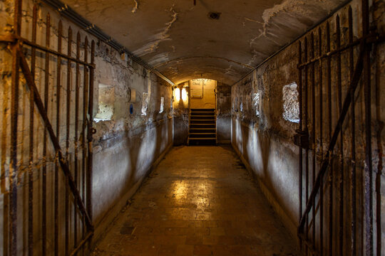 View of the historic stone corridor inside Fort Pampus with iron gates, vaulted ceiling, and stairs leading to an upper level in Gooise Meren, North Holland, Netherlands.
