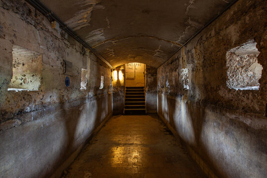 View of the interior of the historic Fort Pampus, featuring weathered stone walls, an arched ceiling, and small embrasures leading to a staircase in Gooise Meren, North Holland, Netherlands.