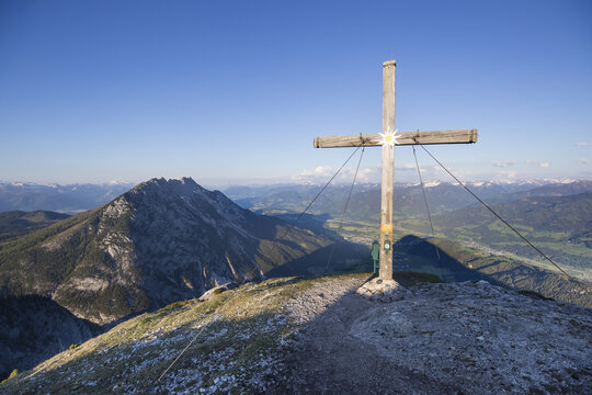 View of the summit cross on Stoderzinken mountain peak overlooking the Ennstal valley and Schladming region with rocky terrain and clear blue sky in Stoderzinken, Steiermark, Austria.