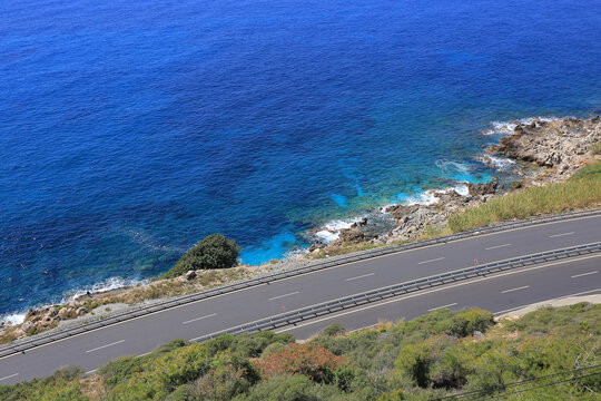 High angle view of a coastal asphalt road next to a deep blue sea