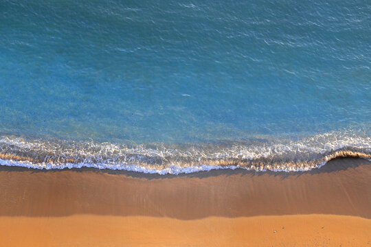 Abstract natural background texture of turquoise water foam and golden sand shoreline