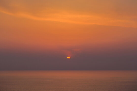 Beautiful sunset over the calm sea horizon with an orange sky