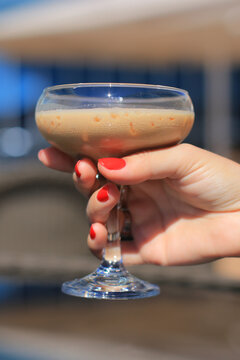 Woman hand with red manicure holding a cocktail glass