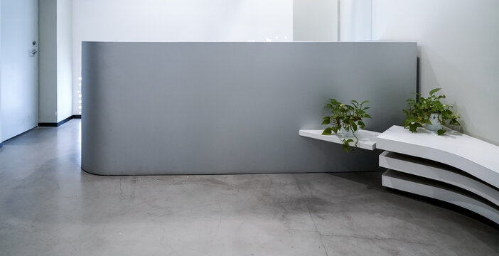 Minimalist grey curved reception desk with white layered bench and green pothos plants in modern office lobby