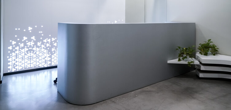Minimalist grey curved reception desk with white layered bench and green pothos plants in modern office lobby