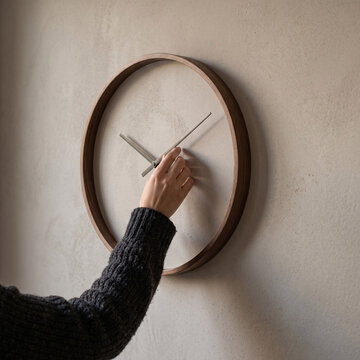 Personne changeant manuellement l&rsquo;heure d&rsquo;une horloge murale