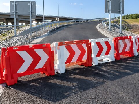 Interlocking modular hollow plastic A-frame barricades with diagonal red and white chevron stripes arranged in a cordon