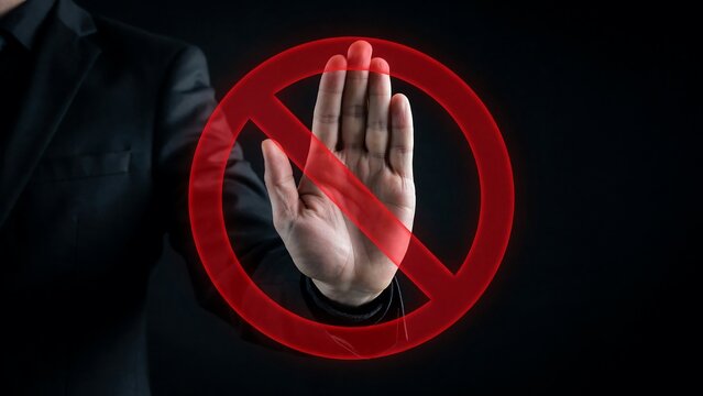 Businessman showing stop gesture with red prohibition sign overlay against dark black background for corporate security