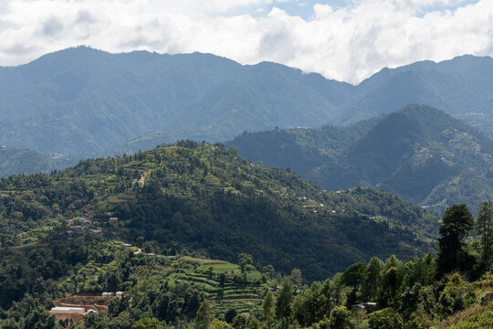 View of the lush terraced fields and rural settlements nestled among the rolling green hills of the Himalayas in Simalchaur Syampati, Bagmati Province, Nepal.