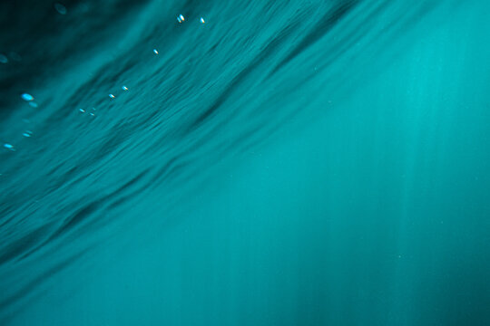 View of the turquoise water surface and light rays penetrating the sea at Lulworth Cove, United Kingdom.
