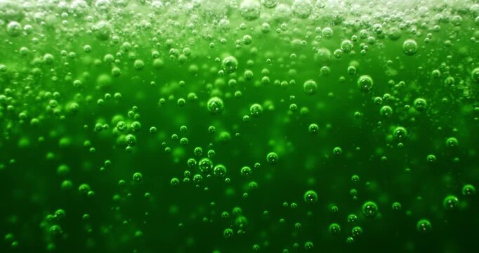 Green liquid with bubbles and fizz. Bubbling green for a festive St Patrick's day drink or a scary witches brew for eerie Halloween backgrounds. Science background of a toxic chemical reaction.