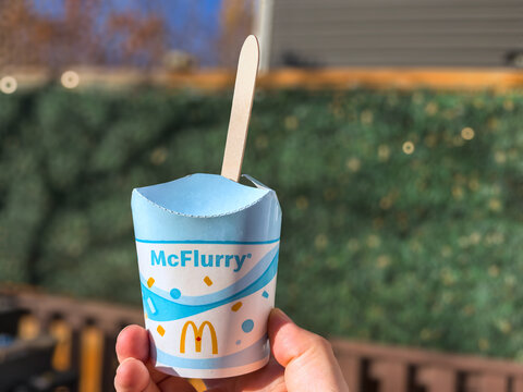 Calgary, Alberta, Canada. Oct 20, 2026. Close up of hand holding McDonald's McFlurry ice cream cup with wooden spoon outdoors on fall day.