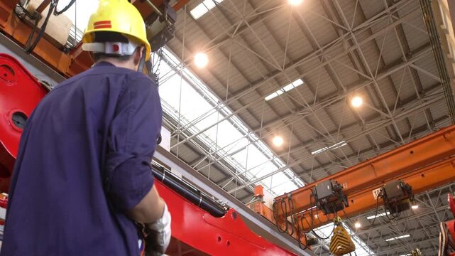 Engineer technician worker in hard hat working at industrial production plant inspects large control panel buttons clipboard in hand, operates large machinery robotic parts to increase productivity