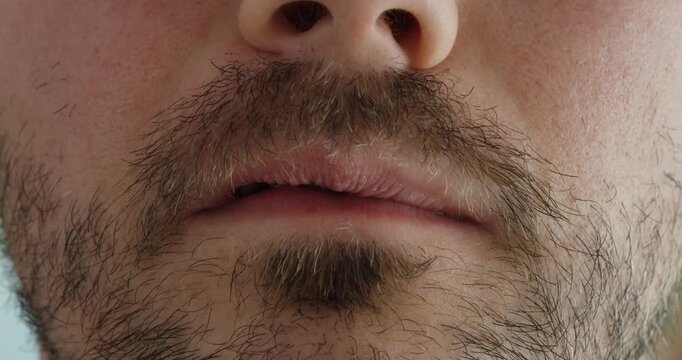 Extreme close up of a man using his fingers to position a small snus pouch beneath his lower lip