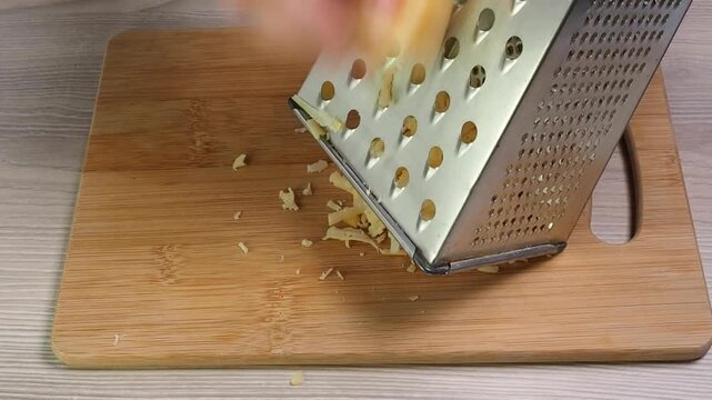 Grate the cheese. Chop the cheese on a wooden board to sprinkle on the dish.