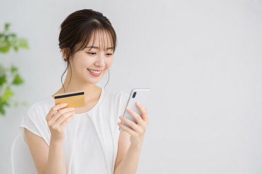 スマートフォンとクレジットカードで決済する女性