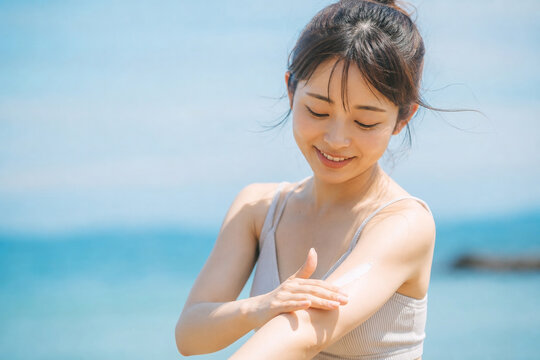 海辺で腕に日焼け止めを塗る女性