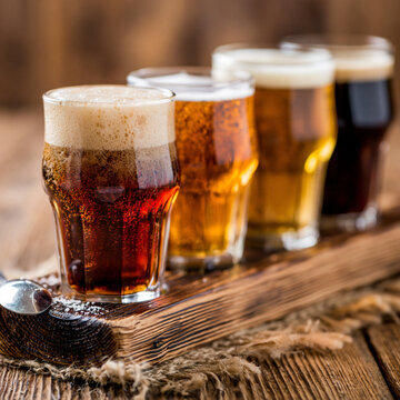 Flight of various craft beer glasses served on a rustic wooden plank with board